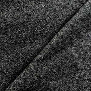 May include: Close-up of a dark gray fabric with a textured surface. The fabric is folded in half, creating a diagonal line across the image.
