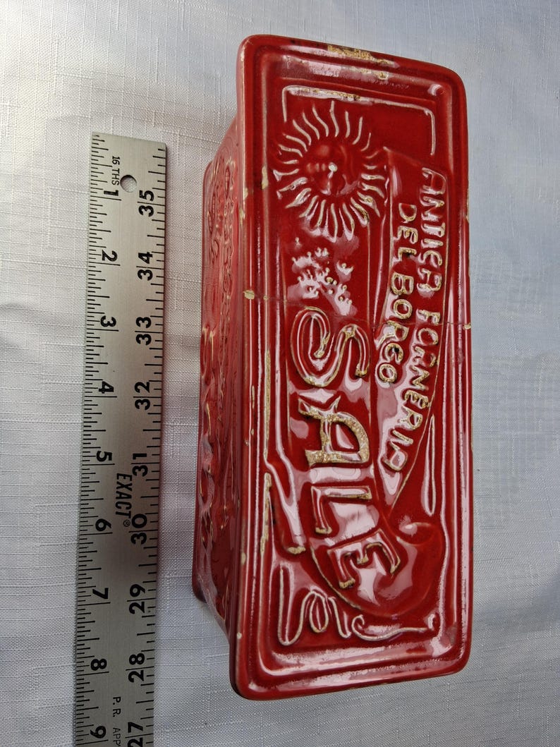 Puede incluir: Un recipiente rectangular de cer&aacute;mica roja con texto y dise&ntilde;os en relieve. El texto incluye la palabra "SALE" y "ANTICA FORNERIA DEL BORGO". El recipiente mide aproximadamente 30 cm de alto.