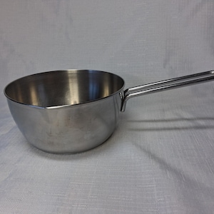 May include: A stainless steel saucepan with a long, tubular handle. The pan has a rounded bowl shape and a shiny, reflective surface. The handle is attached to the side of the pan and is designed for easy gripping. The pan is likely used for cooking.
