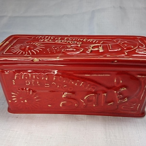 Puede incluir: Una caja rectangular de cer&aacute;mica roja con tapa. La caja tiene texto y dise&ntilde;os en relieve, incluyendo la palabra "SALE" y la frase "ANTICA FORNERIA DEL BORGO". La caja es probablemente vintage o antigua.