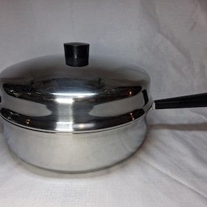 May include: A stainless steel cooking pot with a lid and a black handle. The pot has a rounded shape and a shiny surface. The lid has a black knob. The handle is attached to the side of the pot.