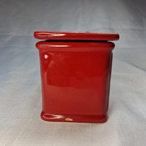 Puede incluir: Un peque&ntilde;o recipiente rectangular de cer&aacute;mica roja con tapa a juego. El recipiente tiene un acabado brillante y una base ligeramente redondeada. La tapa encaja a ras. Para almacenamiento o exhibici&oacute;n.