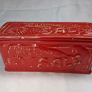 Puede incluir: Una caja rectangular de cer&aacute;mica roja con tapa. La caja tiene texto y dise&ntilde;os en relieve, incluyendo la palabra "SALE" y la frase "ANTICA FORNERIA DEL BORGO". La caja es probablemente vintage o antigua.