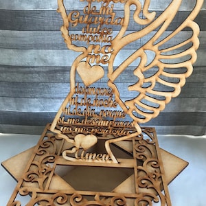 May include: Wooden angel-shaped decoration with the text "Angel de mi Guarda dulce compania no me desampares ni de noche ni de dia porque si me desamparas yo me perderia Amen". The angel has wings and a halo.