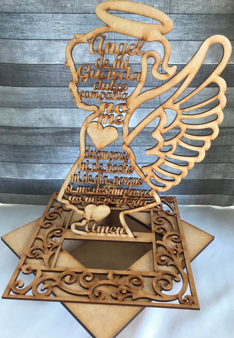 May include: Wooden angel-shaped decoration with the text "Angel de mi Guarda dulce compania no me desampares ni de noche ni de dia porque si me desamparas yo me perderia Amen". The angel has wings and a halo.