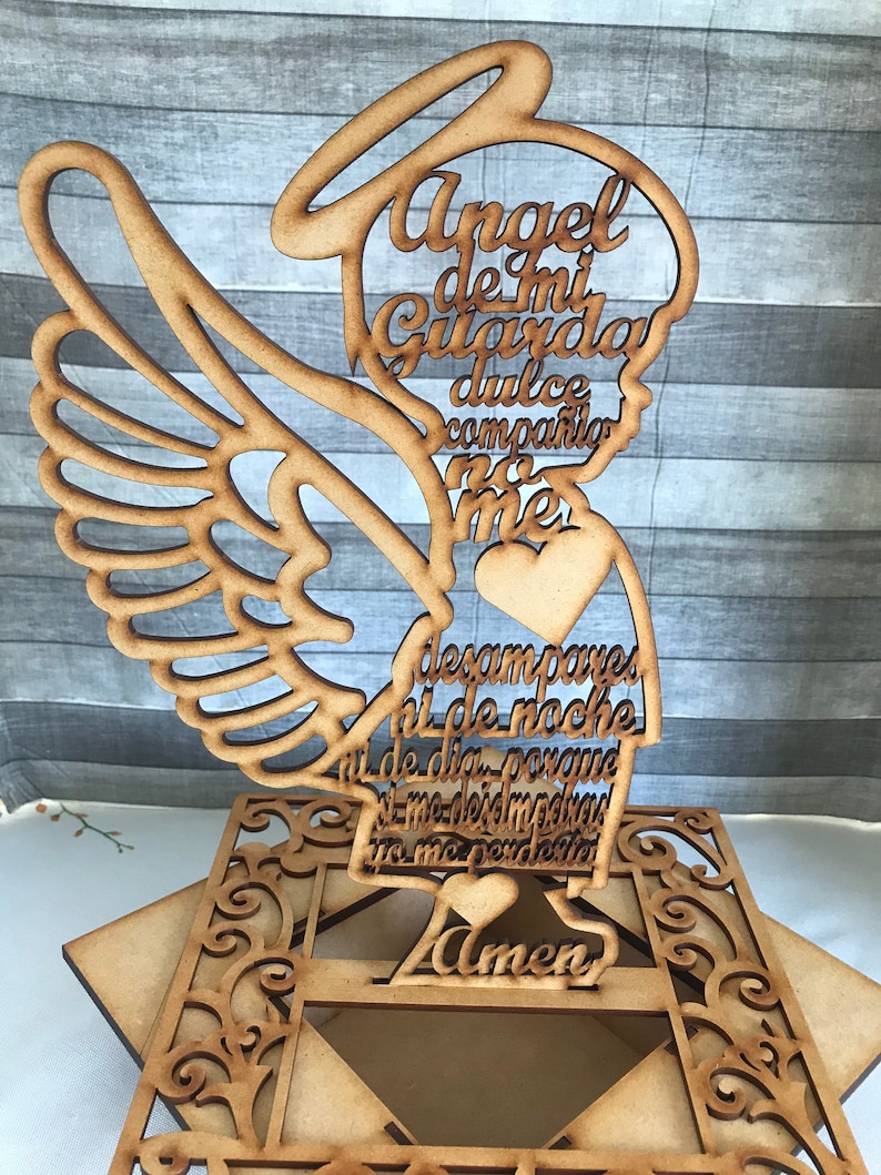 Puede incluir: Un recorte de madera de un &aacute;ngel con alas, un halo y un coraz&oacute;n. El &aacute;ngel sostiene un rollo con el texto "Angel de mi Guarda dulce compania no me desampares ni de noche ni de dia porque si me desmayara tu me perdones Amen".