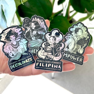 May include: Set of five iridescent holographic stickers featuring illustrations of women with empowering messages. The stickers feature the text "Decolonize", "Beautiful, Fierce, Fiery, Feminist Filipina", and "Empower".