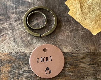 May include: A copper keychain with a round tag that says "MOCHA" and a small coffee cup icon. The keychain is attached to a split ring.