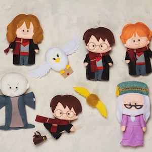 May include: A collection of felt Harry Potter character dolls, including Harry, Hermione, Ron, Dumbledore, Voldemort, and Hedwig the owl. Each doll is dressed in character-specific attire, with vibrant colors and detailed features. A golden snitch and Harry on a broom are also included.