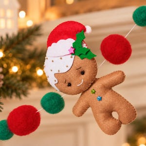 May include: A felt garland featuring a brown gingerbread person ornament wearing a red and white Santa hat with green holly leaves. The garland is strung with alternating red and green felt balls, creating a festive holiday decoration.