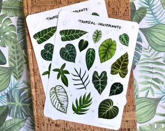 May include: Two white sticker sheets featuring various green tropical houseplant leaf illustrations. The text TROPICAL HOUSEPLANTS is printed at the top of each sheet, accompanied by small star and moon icons scattered among the leaf designs.