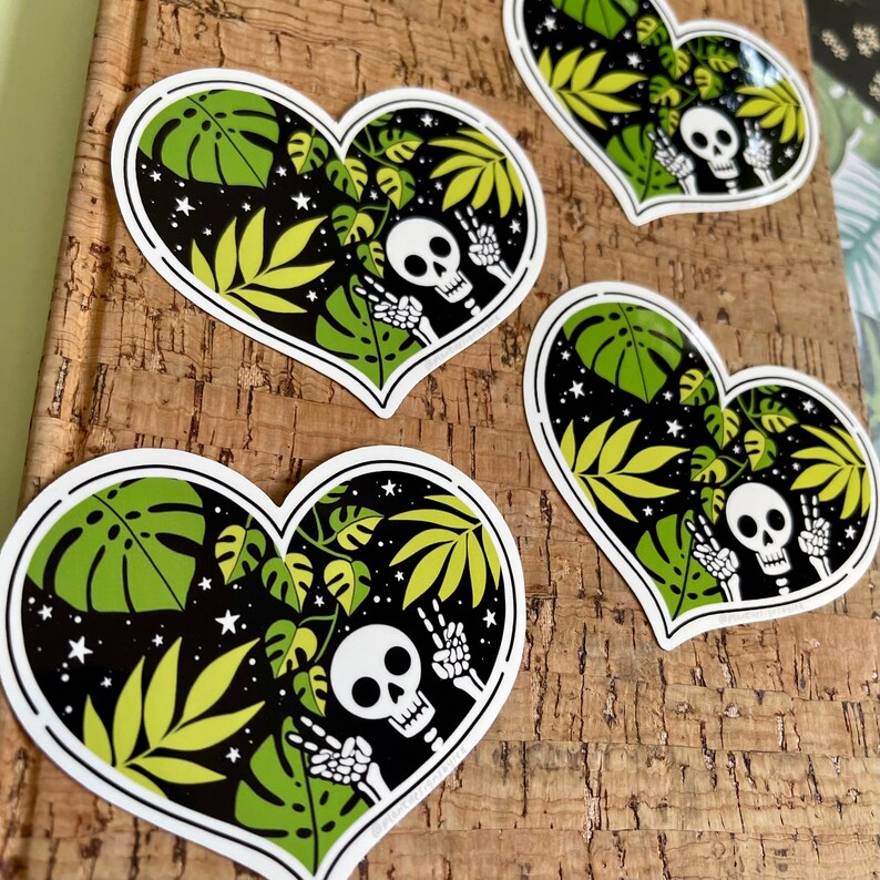 May include: Four heart-shaped stickers with a black background, white stars, and green tropical leaves. Each sticker features a white skeleton with a skull, making a peace sign with its hands.