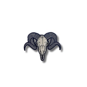 May include: Black enamel pin with a white ram skull design. The ram skull has large, curled horns.