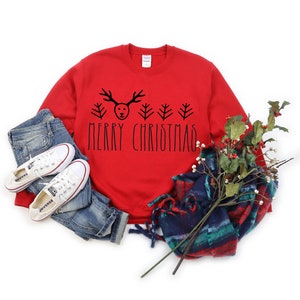 Puede incluir: Sudadera roja de Navidad con un gr&aacute;fico de reno negro y &aacute;rboles de Navidad y el texto "Merry Christmas".