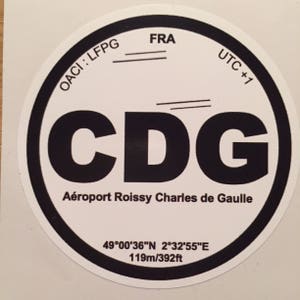 Peut inclure: Un autocollant circulaire avec une bordure noire et un fond blanc. Il affiche les lettres "CDG" en gras noir, avec le texte "Aéroport Roissy Charles de Gaulle" en dessous. D'autres textes incluent "OACI: LFPG", "FRA", "UTC +1" et des coordonnées.