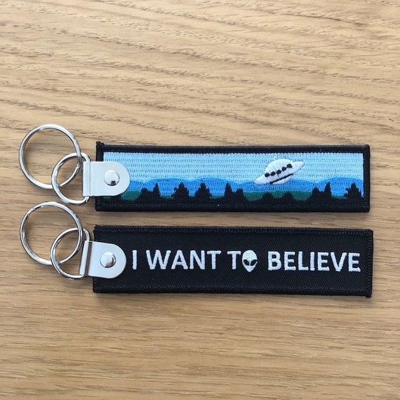 Porte-clé “I Want to Believe” – Brille dans le noir – Accessoire Geek / Sci-Fi – Cadeau UFO & X-Files – Tissu brodé
