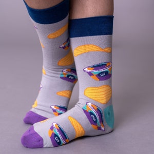 May include: A pair of gray socks with a blue cuff and a pattern of yellow chips and purple containers with the word "DIP" on them.