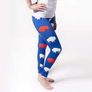 May include: Blue leggings with a pattern of white and red buffalo silhouettes.