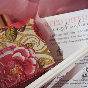 May include: A floral patterned reed diffuser bottle with a gold lid and white reeds. The instructions on the card read "Reed Diffuser instructions Diffuser will take up to 48 hours to absorb fragrance. The more reeds the more aroma - start low and work up to... To refresh the fragrance, carefully flip the reeds every week."
