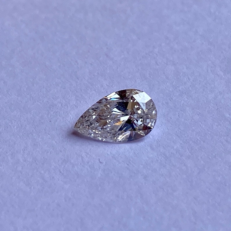 May include: A pear-shaped diamond gemstone with a clear, brilliant cut. The diamond is set against a white background.