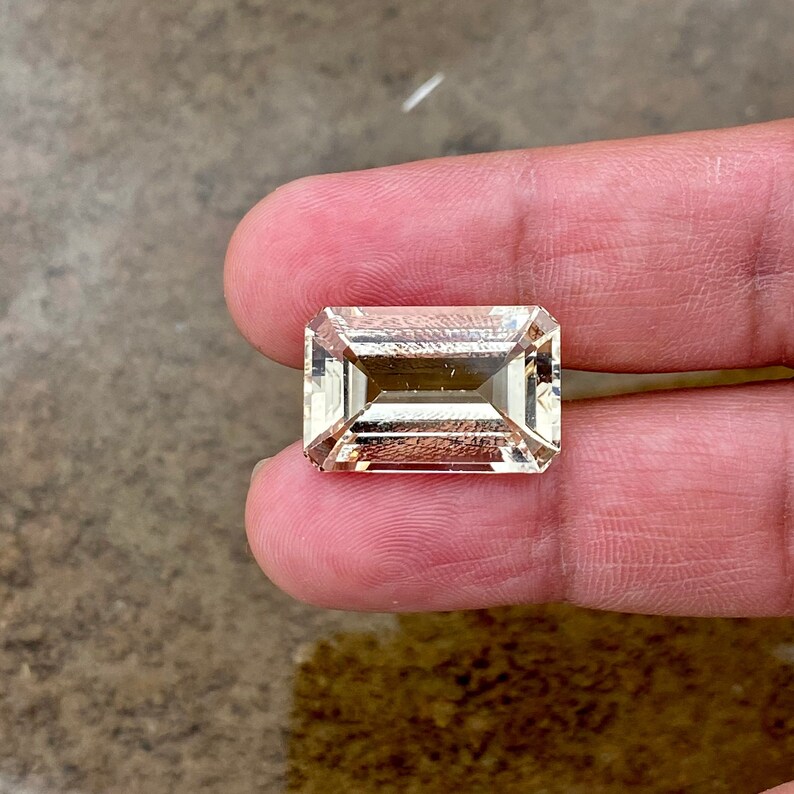 May include: A light brown, rectangular, faceted gemstone with a step cut.