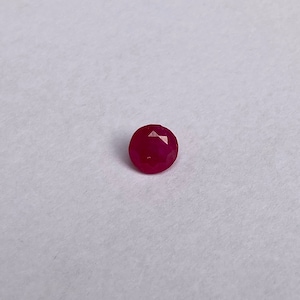 Op de afbeelding: Een dieprode robijn edelsteen met een facetgeslepen vorm.