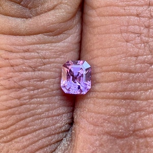 May include: A square-shaped, light purple gemstone with a faceted cut.
