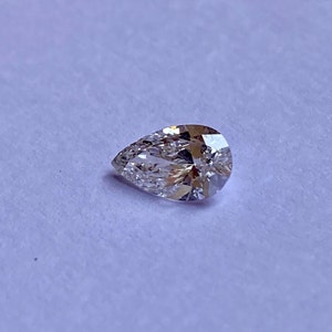 May include: A pear-shaped diamond gemstone with a clear, brilliant cut. The diamond is set on a white background.