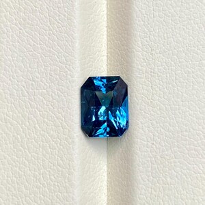 May include: A deep blue gemstone with a rectangular emerald cut.