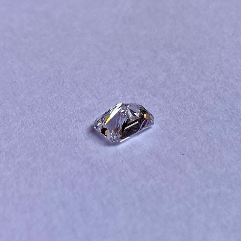 以下が含まれることがあります： わずかに黄色がかった透明な長方形のファセットカットの宝石