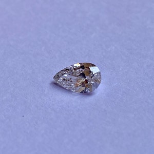 May include: A pear-shaped diamond gemstone with a clear, brilliant cut. The diamond is set against a white background.