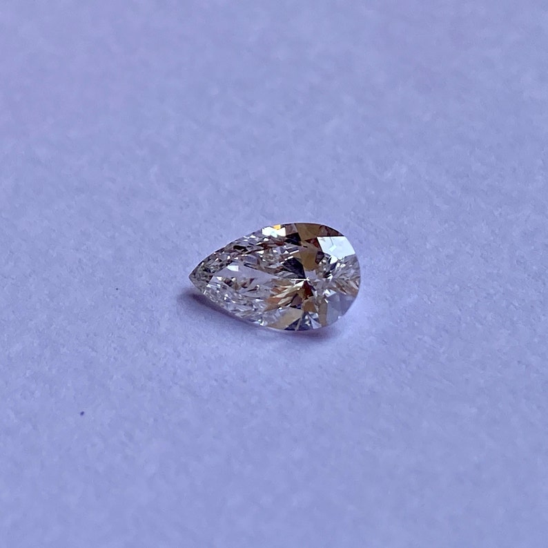 May include: A pear-shaped diamond gemstone with a clear, brilliant cut. The diamond is set against a white background.