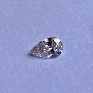 May include: A pear-shaped diamond gemstone with a clear, brilliant cut. The diamond is set on a white background.