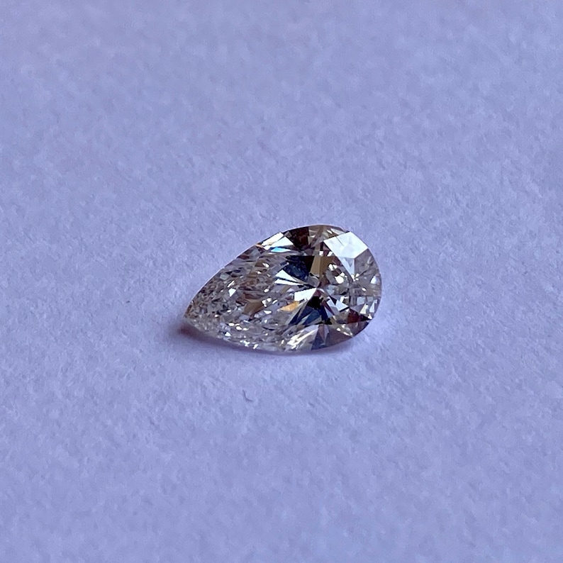 May include: A pear-shaped diamond gemstone with a clear, brilliant cut. The diamond is set on a white background.