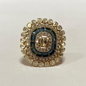 May include: A gold ring with a large, round, blue and white center stone surrounded by smaller white stones.