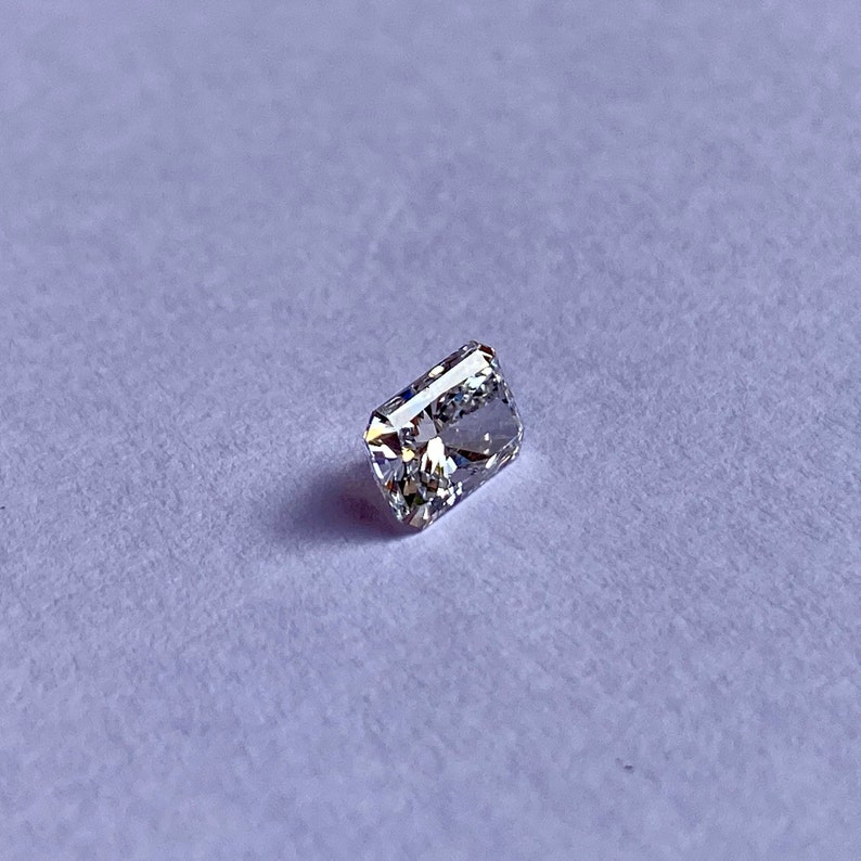 以下が含まれることがあります： わずかに黄色がかった透明な長方形のファセットカットの宝石