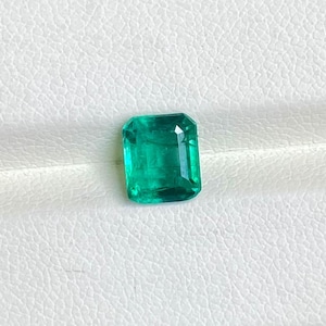 May include: A vibrant green emerald gemstone, cut in a rectangular emerald shape.