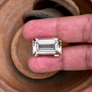 May include: A light brown, rectangular, faceted gemstone with a clear, glassy appearance.