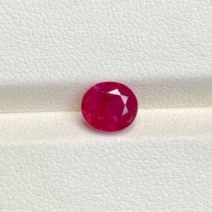 May include: A round, faceted ruby gemstone with a deep red hue. The gemstone is set against a white background, showcasing its brilliant cut and colour. This gemstone is ideal for jewellery making.
