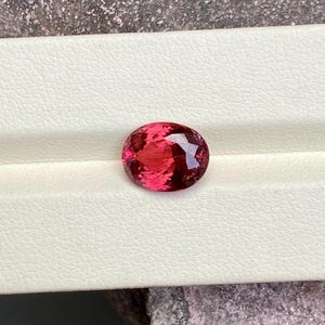 K&ouml;nnte beinhalten: Ein lebhafter, ovaler Edelstein in Pink mit einer glatten, polierten Oberfl&auml;che.