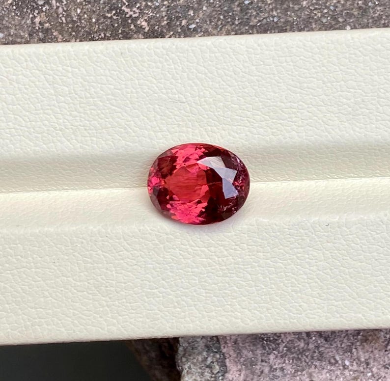 K&ouml;nnte beinhalten: Ein lebhafter, ovaler Edelstein in Pink mit einer glatten, polierten Oberfl&auml;che.