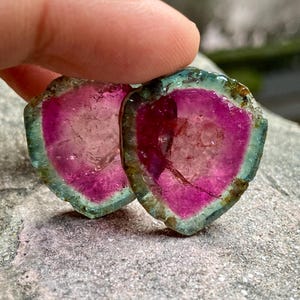 Pu&ograve; includere: Due fette di gemme rosa, verdi e trasparenti con un bordo grezzo e naturale. Le fette sono traslucide e presentano un motivo stratificato e striato.