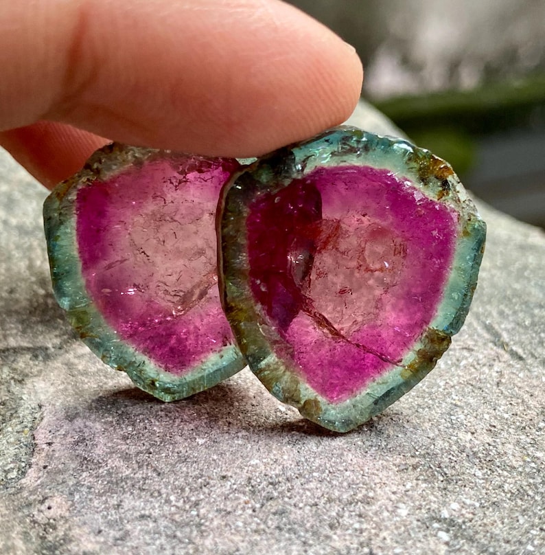 Pu&ograve; includere: Due fette di gemme rosa, verdi e trasparenti con un bordo grezzo e naturale. Le fette sono traslucide e presentano un motivo stratificato e striato.