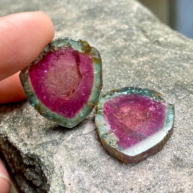 Pu&ograve; includere: Due fette di tormalina rosa, verde e argento con un aspetto stratificato, simile a un cristallo.