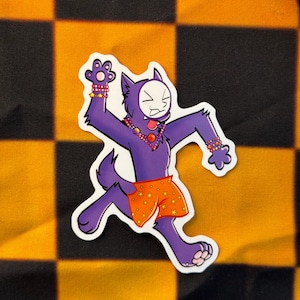 以下が含まれることがあります： 白いマスク、星模様のオレンジ色のショートパンツ、宝石を身につけた紫色の漫画のオオカミのステッカー。オオカミは腕を上げたランニングポーズをとっています。背景は黒とオレンジのチェック柄です。