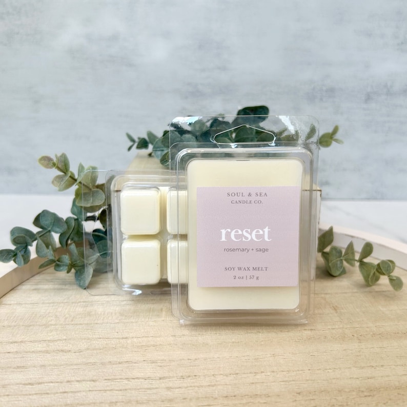 Puede incluir: Un paquete de pl&aacute;stico transparente que contiene cuatro cubos de cera de soja blanca. La etiqueta dice "SOUL & SEA CANDLE CO. reset rosemary + sage SOY WAX MELT 2 oz | 57 g"