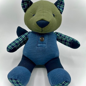 May include: A plush toy bear made from repurposed fabric. The bear is green, blue, and black with a plaid pattern on the ears, arms, and feet.