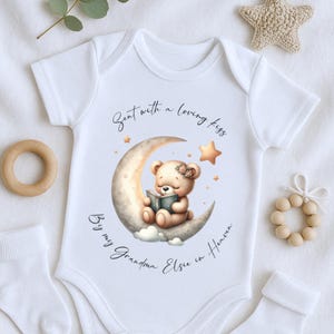 Könnte beinhalten: Weißer Baby-Strampler mit einer niedlichen Illustration eines Teddybären, der auf einem Halbmond sitzt und ein Buch liest. Der Text lautet "Sent with a loving kiss Big my Grandma Elsie in Heaven".