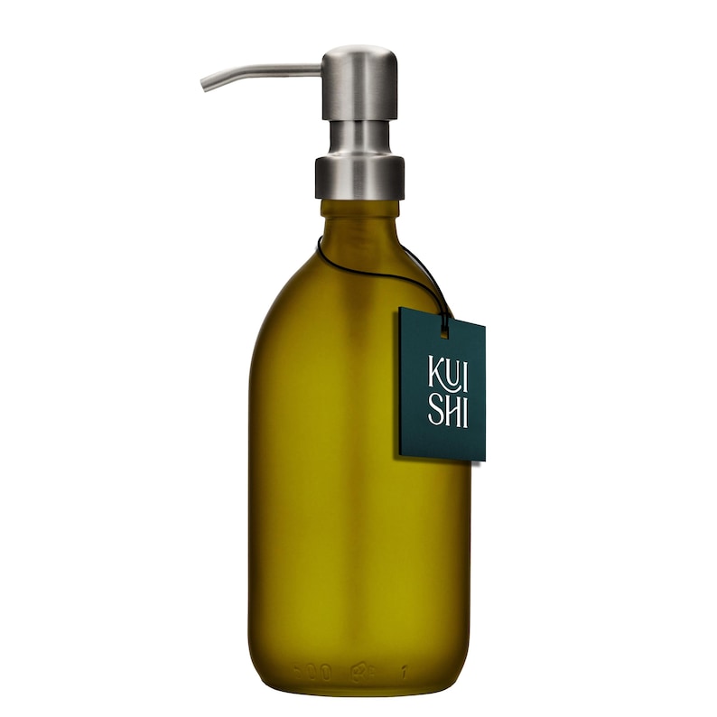 May include: A frosted amber glass bottle with a stainless steel pump dispenser. The bottle has a black tag with the word "KUI SHI" printed in white.