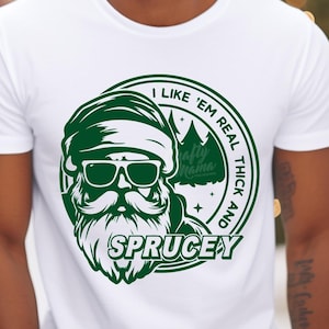 May include: White t-shirt with a green graphic of a Santa Claus wearing sunglasses and a hat. The graphic says "I like 'em real thick and spruce-y".